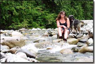 Briard-Artemis and Barbara sitting by a stream in BC